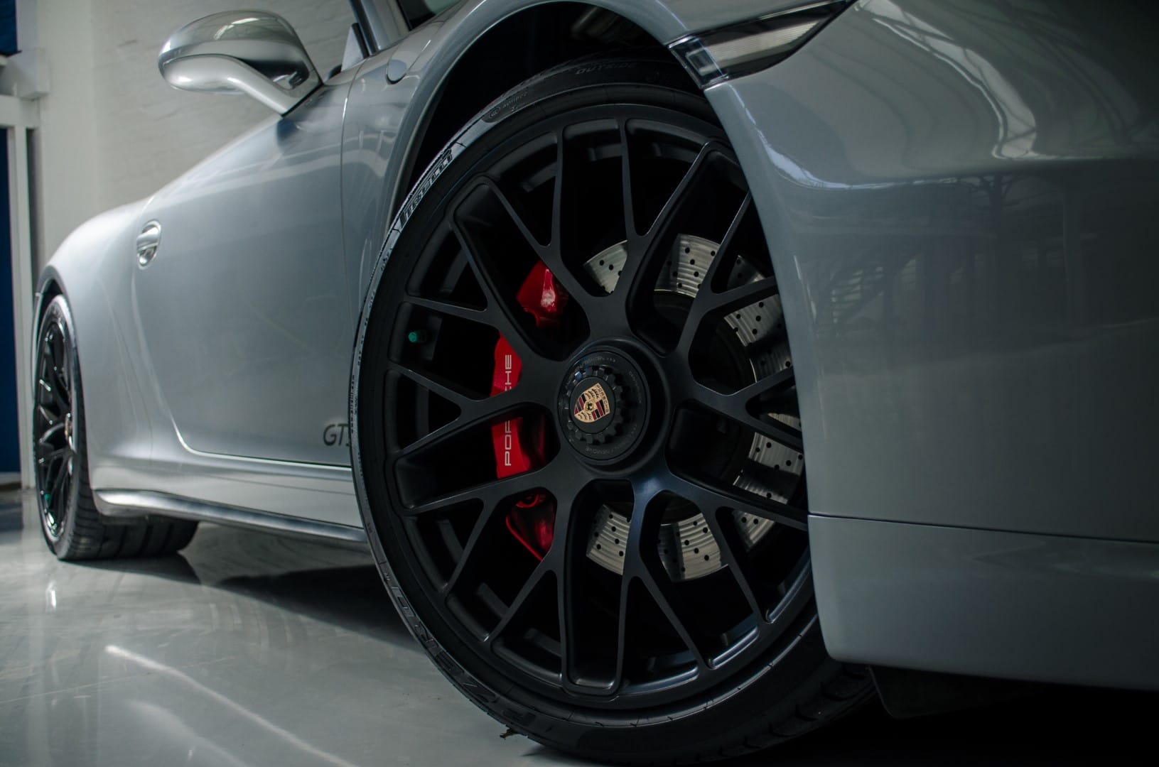 Close-up of a car wheel with a distinctive rim design on a white car.